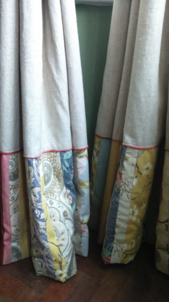 Remnants and Scraps - image of oatmeal coloured curtains with deep patchwork border made from remnants strips, and fabric-covered cord piping edge