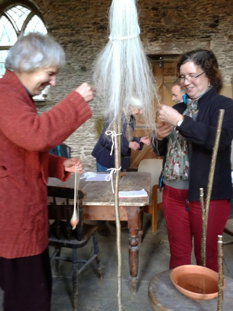 Warp-weighted Loom weaving: image of workshop attendees spinning flax from a distaff