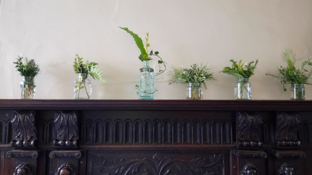Resourceful wedding foliage - Image of foliage in bottles on mantlepeice