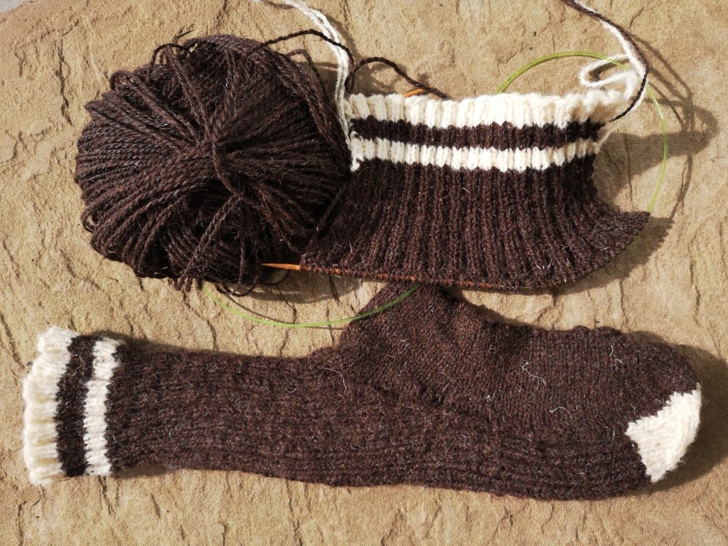 Refootable socks and the mending culture revival - image of a complete hand-knitted refootable sock and a part-complete sock, showing the sock upper knitted flat