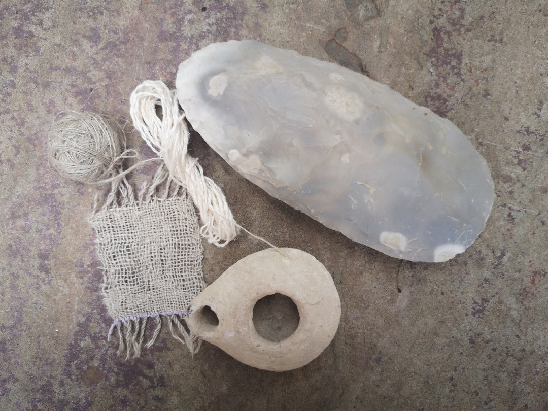 Ancestral Living: Image of a prehistoric hand axe, a small Roman lamp, a Swatch of hand-woven linen and handspun nettle yarn