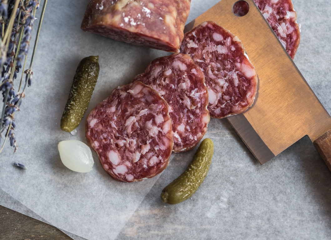 Charcuterie in the Pantry: image of slices of salami on a chopping board with gherkins and pickled onion, by Jez Timms on Unsplash