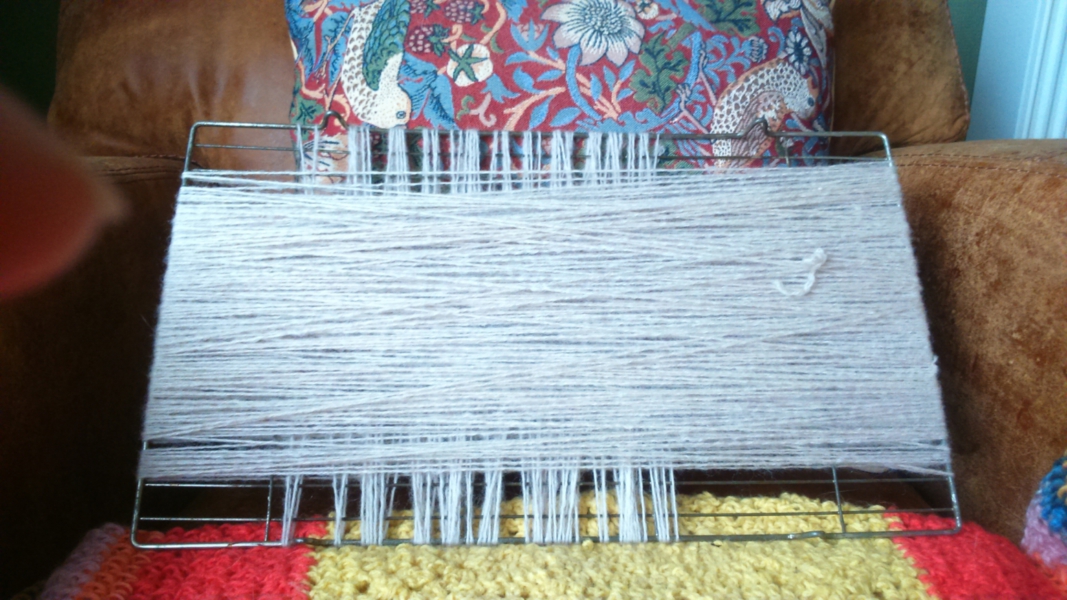 How to straighten unravelled wool: Image of unravelled wool wound round a cake drying rack to dry - sitting on a crochet blanket and propped up in an armchair