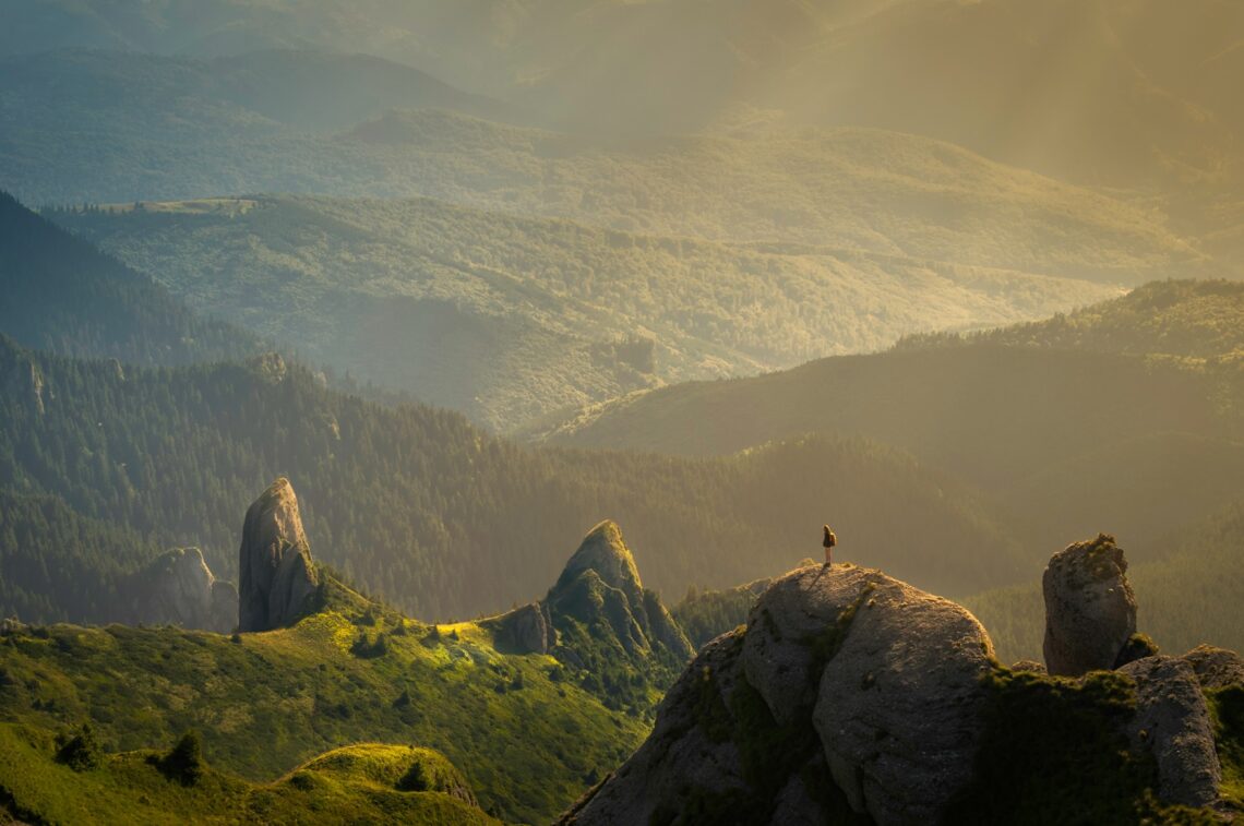 Alternative platforms: lone person on a promontary looking out into a dark hilly landscape