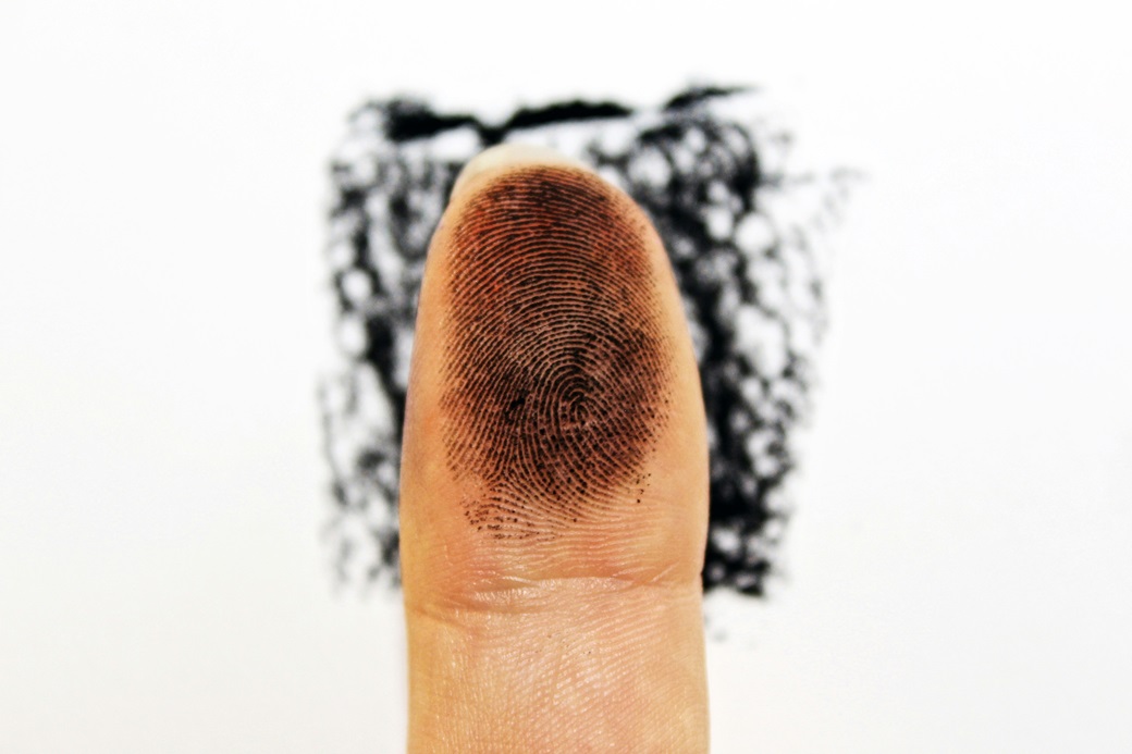 Fingerprint: Image of an inked finger tip showing the fingerprint, to suggest fingerprints at a crime scene (an analogy for microbes as possible causes of disease or death in a person.)